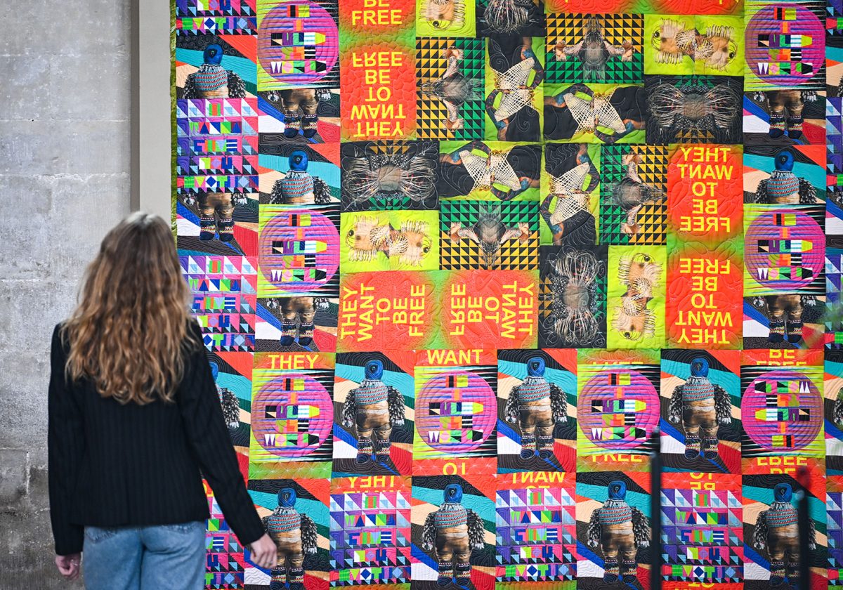 Woman looking at a colourful quilt that is hung inside Salisbury Cathedral