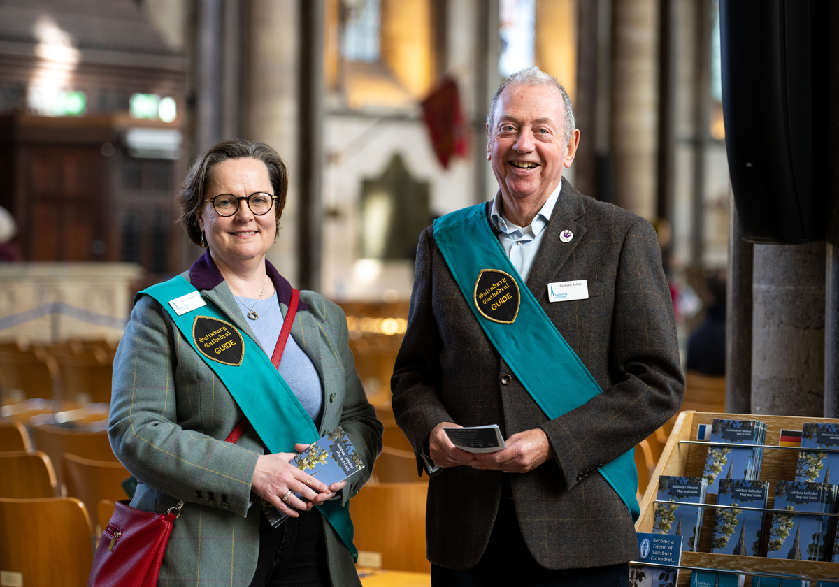 A man and a woman looking at the camera, smiling. They are wearing Volunteer sashes