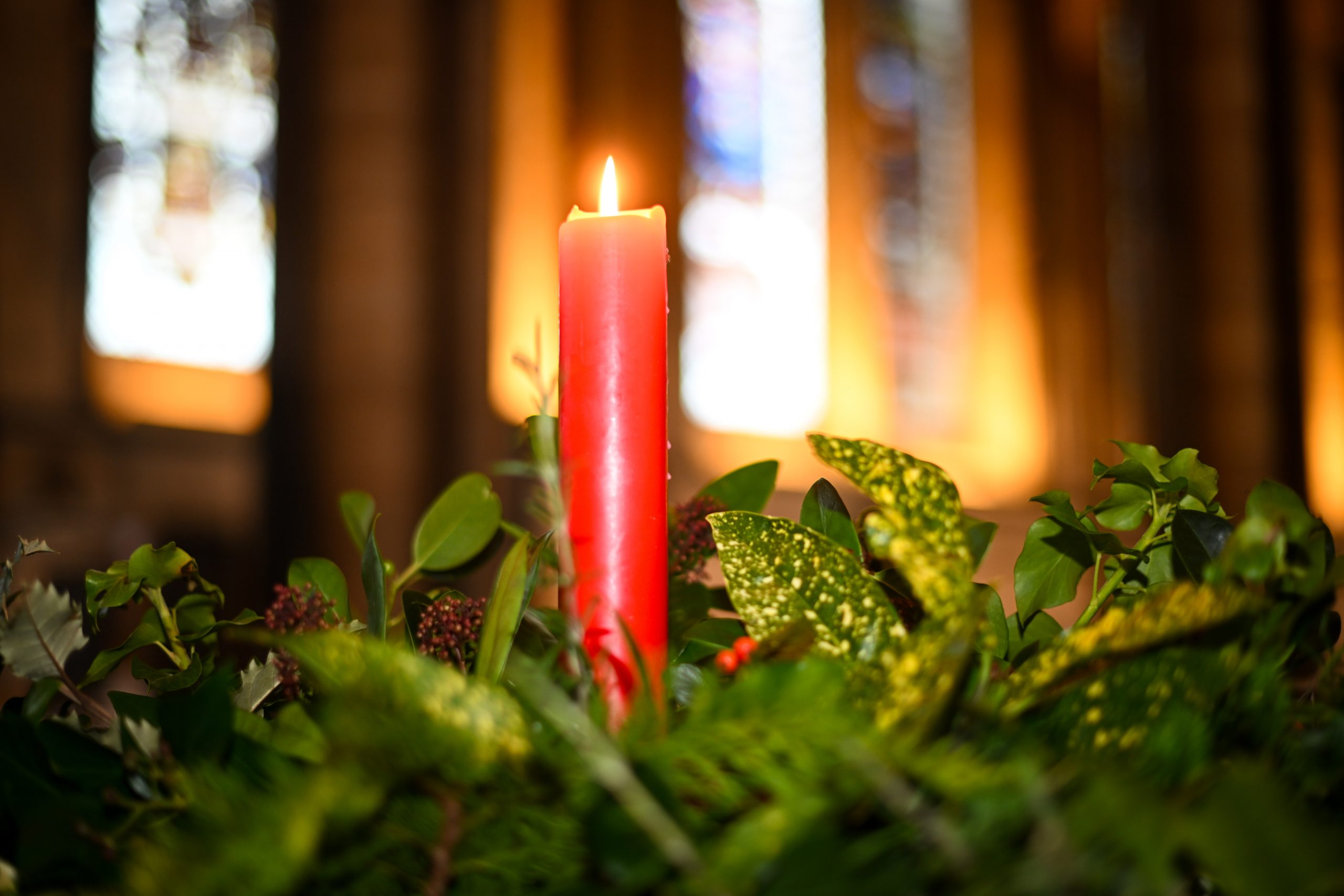 Red candle alight amongst winter foliage