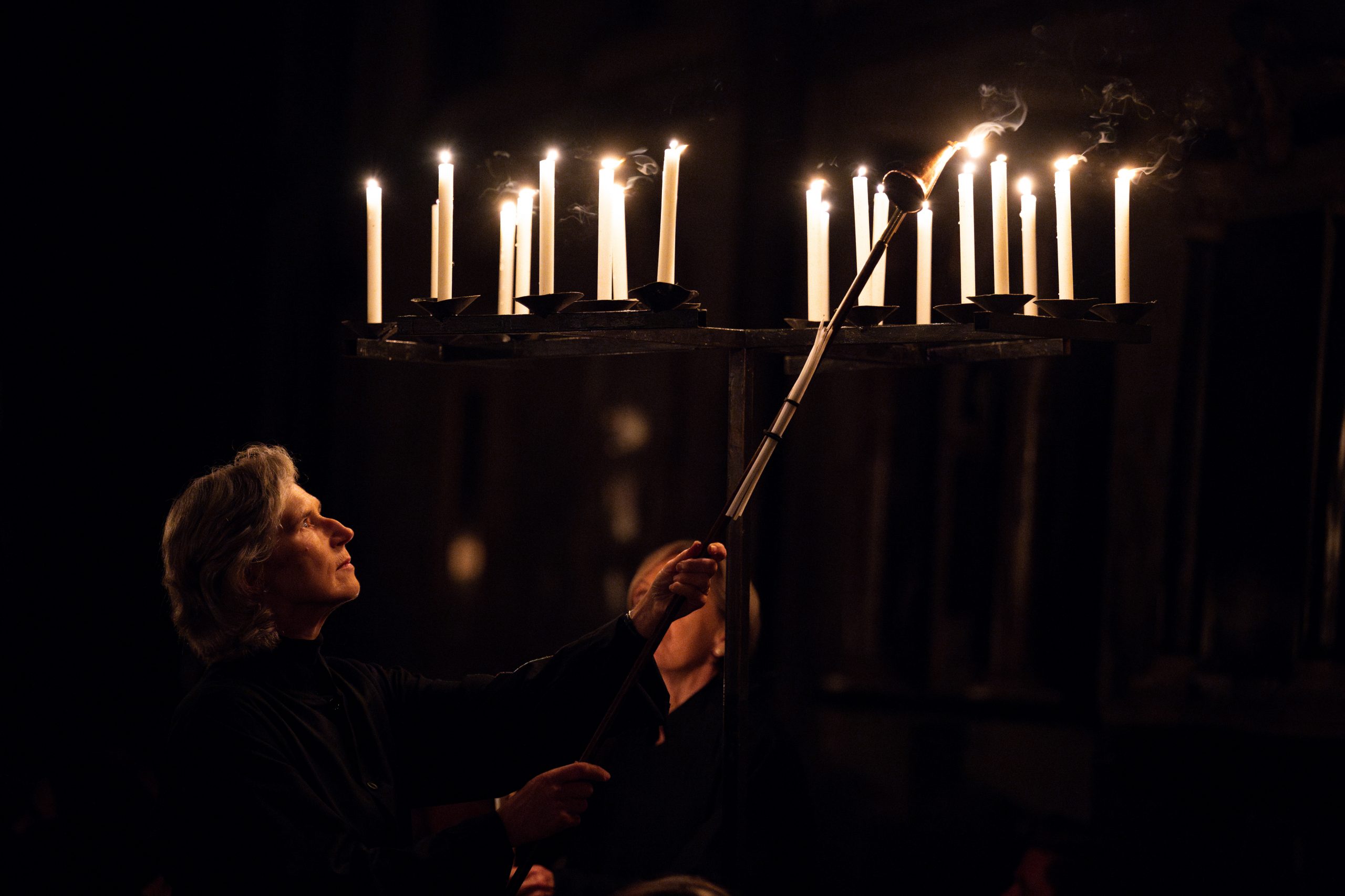 Woman lights candles in a dark cathedral
